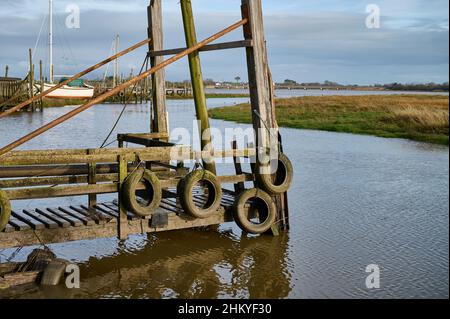 Pneumatici auto per proteggere sia le barche e jetty in legno su Skippool Creek in alta marea Foto Stock