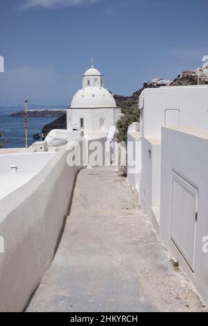 Un tipico vicolo che conduce ad una cappella ortodossa imbiancata sull'isola di Santorini in Grecia Foto Stock