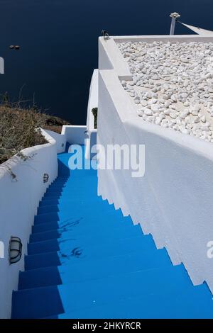 Santorini, Grecia - 7 maggio 2021 : scalinata blu che conduce ad un edificio residenziale con una bella vista sul Mar Egeo e sul vulcano di Santor Foto Stock