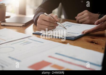 Primo piano di un uomo d'affari che discute di grafici di analisi o grafici su un tavolo da lavoro e utilizzando un computer portatile. Primo piano analisi maschile e concetto di strategia. Foto Stock