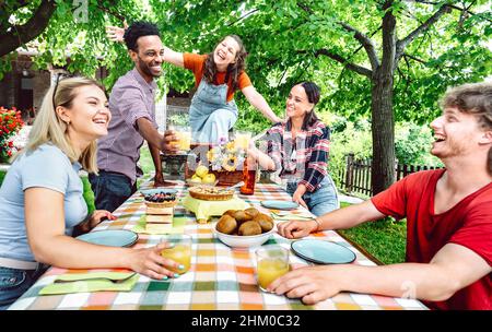 Giovani uomini e donne che tostano sano succo di frutta d'arancia al pic-nic della fattoria patio - concetto di stile di vita con amici felici che si divertono insieme su afte Foto Stock