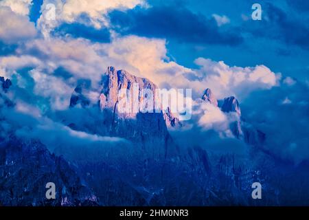 Campanile e cima di Val di Roda (al centro), Sass Maor e cima della Madonna (a destra), cime principali del gruppo pala, ricoperte di nuvole, al tramonto. Foto Stock