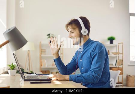 Un uomo sorridente nelle cuffie parla durante una videochiamata sul computer Foto Stock