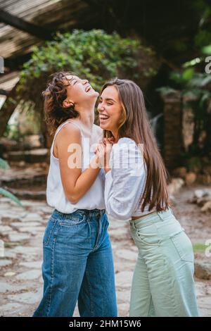 Due giovani adolescenti ragazza amici ridendo circondato da piante Foto Stock