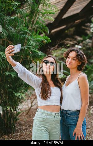 Due giovani ragazze adolescenti che prendono un selfie al parco mentre si diverte. Foto Stock