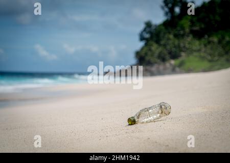 rifiuti di plastica lavati in su dall'oceano su sabbia bianca spiaggia onde dolci in paradiso montagna sfondo inquinamento Foto Stock