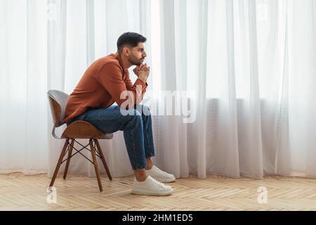 Uomo arabo pensivo seduto su sedia e pensiero Foto Stock