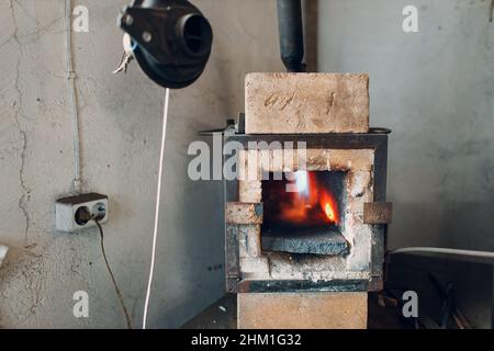 Forno di fucina con fiamma calda. Smith scaldante pezzo di acciaio in fuoco di fucina rosso-caldo. Foto Stock