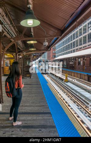 Una persona sul binario della stazione in attesa di un treno Chicago L che arriva alla stazione di Quincy. Foto Stock