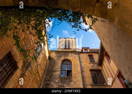 Il cortile di un'abbazia medievale in pietra gialla francese situata a Sarlat-la-Caneda, Perigord, Francia, in un soleggiato pomeriggio autunnale Foto Stock