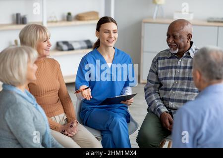 Psicologa giovane amichevole che ha conversato con gli anziani Foto Stock