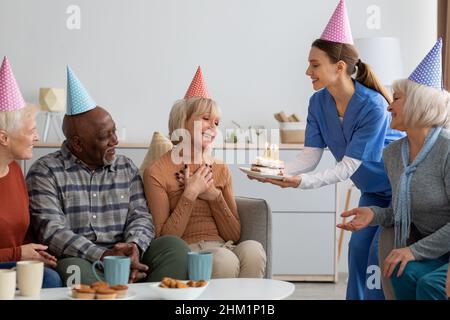 Donna anziana che ha festa di compleanno a casa di cura Foto Stock