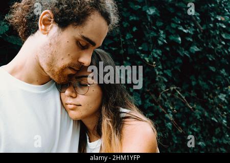 Una giovane e naturale coppia spagnola si agganava fronte di alcune foglie Foto Stock