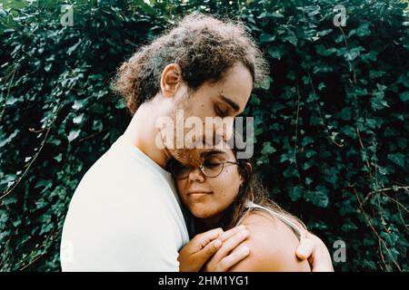 Una giovane coppia spagnola si agganava di fronte alcune foglie Foto Stock