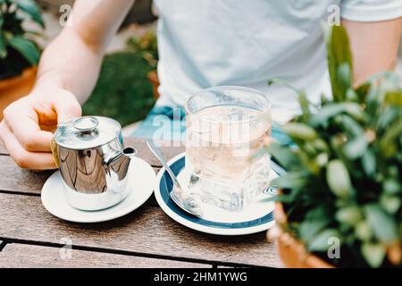 Un giovane maschio che si prepara a preparare un tè dentro un bar moderno Foto Stock