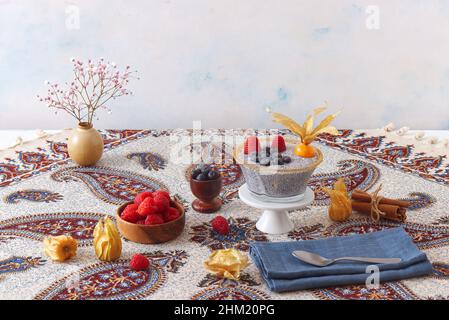Vista ad angolo basso del dessert chia budino con bacche estive, lamponi, mirtilli, banane e physalis. Foto Stock