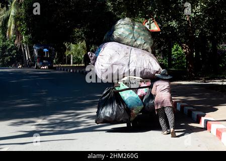 Donna che spinge un carrello caricato di rifiuti riciclabili a Luang Prabang, Laos Foto Stock