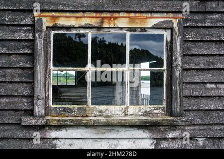 Una finestra di vetro in un capannone di legno che è ben in ritardo alcuni lavori di manutenzione e ristrutturazione. Foto Stock