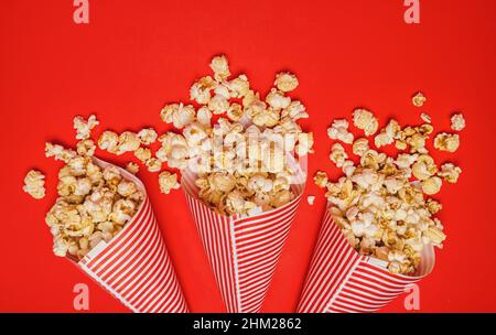 Popcorn versato in sacchetti di carta su sfondo rosso, cinema, film di intrattenimento e carnevale concept immagine Foto Stock