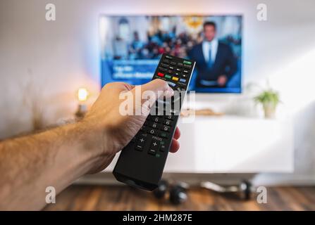 Guardare la TV e utilizzare il telecomando per zap canali, pov shot Foto Stock