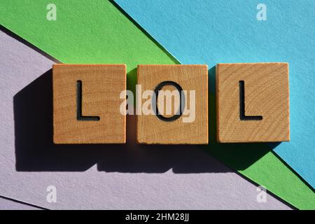 LOL acronimo di Laughing out Loud, in lettere in alfabeto di legno isolato su sfondo colorato Foto Stock