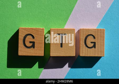 GTG, abbreviazione di Got To Go, utilizzata nella conversazione testuale. Lettere in legno dell'alfabeto isolate su sfondo colorato Foto Stock