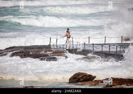 Adolescenti che giocano nell'oceano surf accanto alla piscina di roccia dell'oceano di Avalon Beach a Sydney, NSW, Australia Foto Stock