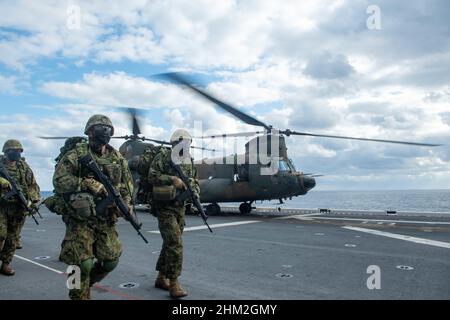 MAR DELLE FILIPPINE (Feb 6, 2022) i membri della Brigata Anfibio Rapid Deployment (ARDB) del Giappone sbarcano un elicottero CH-47J Chinook dalla forza di autodifesa terrestre del Giappone sul ponte di volo della nave d'assalto anfibio dispiegata in avanti USS America (LHA 6) durante Exercise Noble Fusion. Noble Fusion dimostra che le forze navali di spedizione navali stand-in schierate in avanti dalla Marina e dai corpi marini possono rapidamente aggregare le squadre Marine Expeditionary Unit/Amphibious Ready Group in mare, insieme a un gruppo di attacco portaerei, nonché altri elementi di forza congiunta e alleati, al fine di condurre una letale negazione del mare Foto Stock