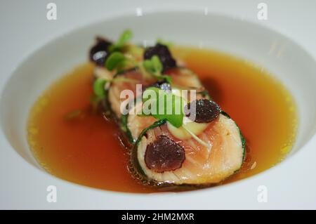 Rotolo di salmone confezionato a Nori con tartufo nero affettato e germogli nel piatto della ciotola per zuppa Foto Stock