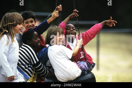 Austin, Texas USA: Gli studenti di seconda e terza classe giocano insieme sull'altalena del pneumatico nel campo da gioco della scuola elementare durante la pausa. ©Bob Daemmrich Foto Stock