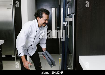 Giovane uomo latino panettiere e forno croissant e pane in cucina in Messico America Latina Foto Stock