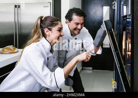 Giovane coppia latina donna e uomo panettieri e croissant da forno e pane in cucina in Messico America Latina Foto Stock