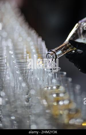 Champagne che si versa in bicchieri da una bottiglia. Spruzzi e gocce. Concetto per le vacanze. Foto Stock