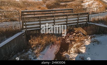 Sentiero pubblico a piedi in inverno con neve e piste. Il sole si pone sulla terra con ombre. Foto Stock