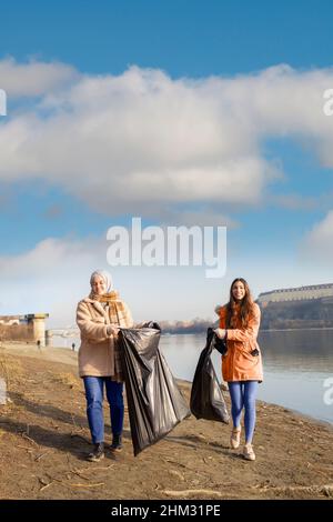 Team di volontari che puliscono la spazzatura da un fiume in una bella giornata Foto Stock