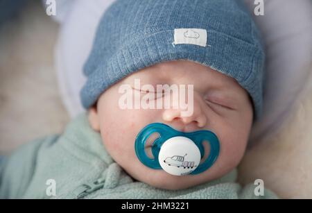 Umea, Norrland Svezia - 11 ottobre 2021: Bambino addormentato con succhietto e cappello blu Foto Stock