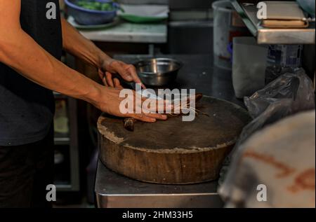 Un venditore di falchi che prepara gamberi o gamberi di grandi dimensioni da grigliare presso un centro di falchi a Singapore Foto Stock