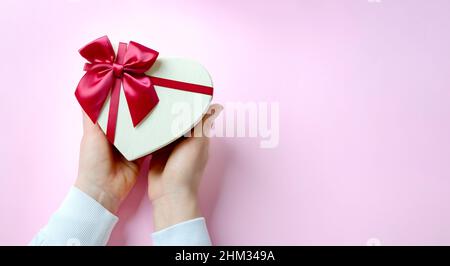 Confezione regalo con nastro rosso su sfondo rosa, spazio copia. San Valentino, vacanze primaverili, Natale e compleanno. Piatto l Foto Stock
