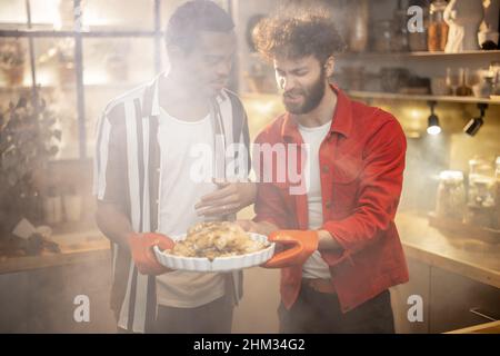 Due ragazzi con pasto cucinato insieme in cucina Foto Stock