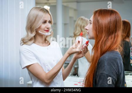 Sopracciglia e labbro sala tatuaggio, cosmetologo e permanente make-up master. Il master seleziona il colore desiderato del pigmento per le labbra e mostra le opzioni al cliente. Cosmetologia della bellezza Foto Stock