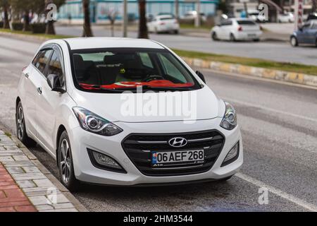 Side, Turchia -25 gennaio 2022: Hyundai i20 bianco è parcheggiato sulla strada in una calda giornata estiva contro la strada e gli alberi Foto Stock