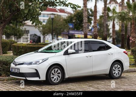 Side, Turchia -25 gennaio 2022: Toyota Corolla bianca è parcheggiata sulla strada in una calda giornata estiva contro il parco Foto Stock