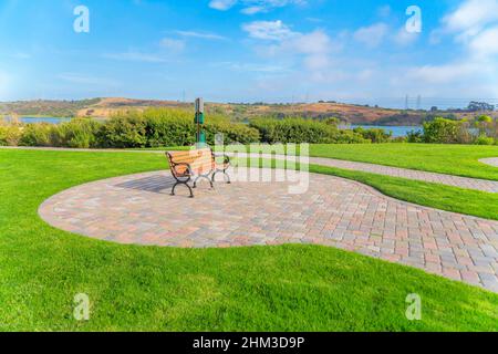 Panca giardino su un terreno in mattoni di pietra vicino alla Laguna di Agua Hedionda a Carlsbad, San Diego, CA Foto Stock