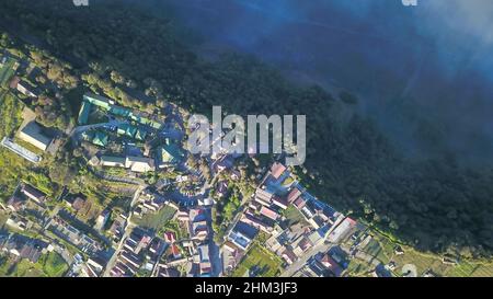 Volo con vista aerea su Cemoro Lawang, piccolo villaggio nella nebbia mattutina. Che si trova sul bordo del massiccio nord-est del Monte bromo, Giava orientale Foto Stock