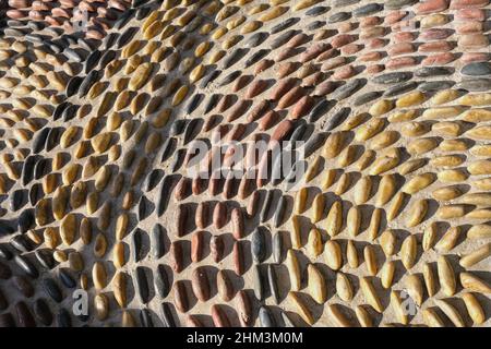 Frammento di riflessologia percorso lastricato per massaggio plantare . Disegno circolare a mosaico da pietre di ciottoli convesse arrotondate Foto Stock