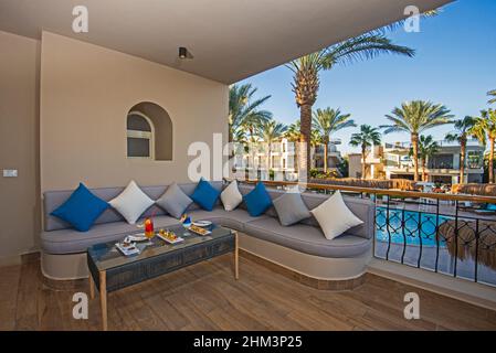 Area patio con terrazza nella lussuosa camera tropicale del resort dell'hotel con divano, area salotto, cocktail, drink e tartine Foto Stock
