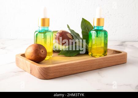 due flaconi cosmetici con pipetta contagocce in vetro colorato con un cosmetico, olio o siero con avocado per la cura quotidiana della pelle Foto Stock