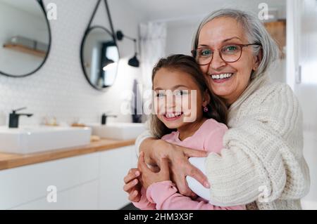 Nonna senior e nonna in piedi in bagno, abbracciando e guardando la macchina fotografica. Foto Stock