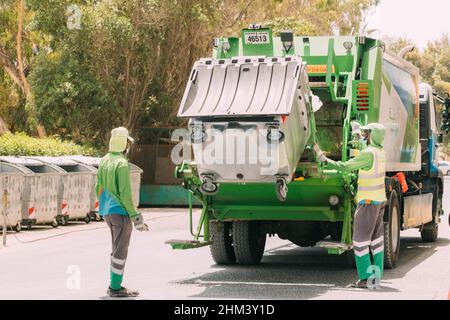 Dubai, Emirati Arabi Uniti - 25 maggio 2021: Lavoratore di riciclaggio municipale spazzatura raccolta camion carico rifiuti e cestino. Uomini lavoratori carico a Foto Stock