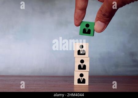 Promozione, leadership e concetto di assunzione. Scegliere a mano i cubi di legno verde con l'icona del dipendente. Spazio di copia per il testo Foto Stock